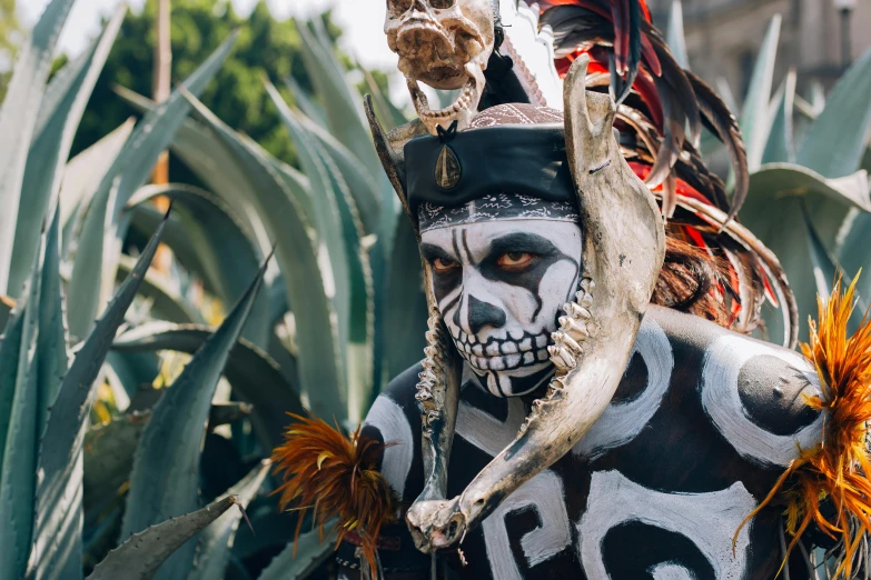 skeleton dressed up with large horns and painted makeup, near plants