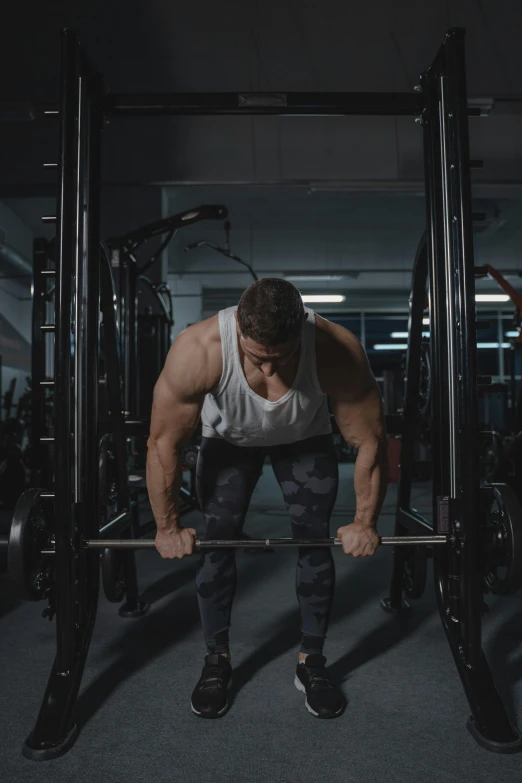 a man with a muscular body is performing squats in a gym