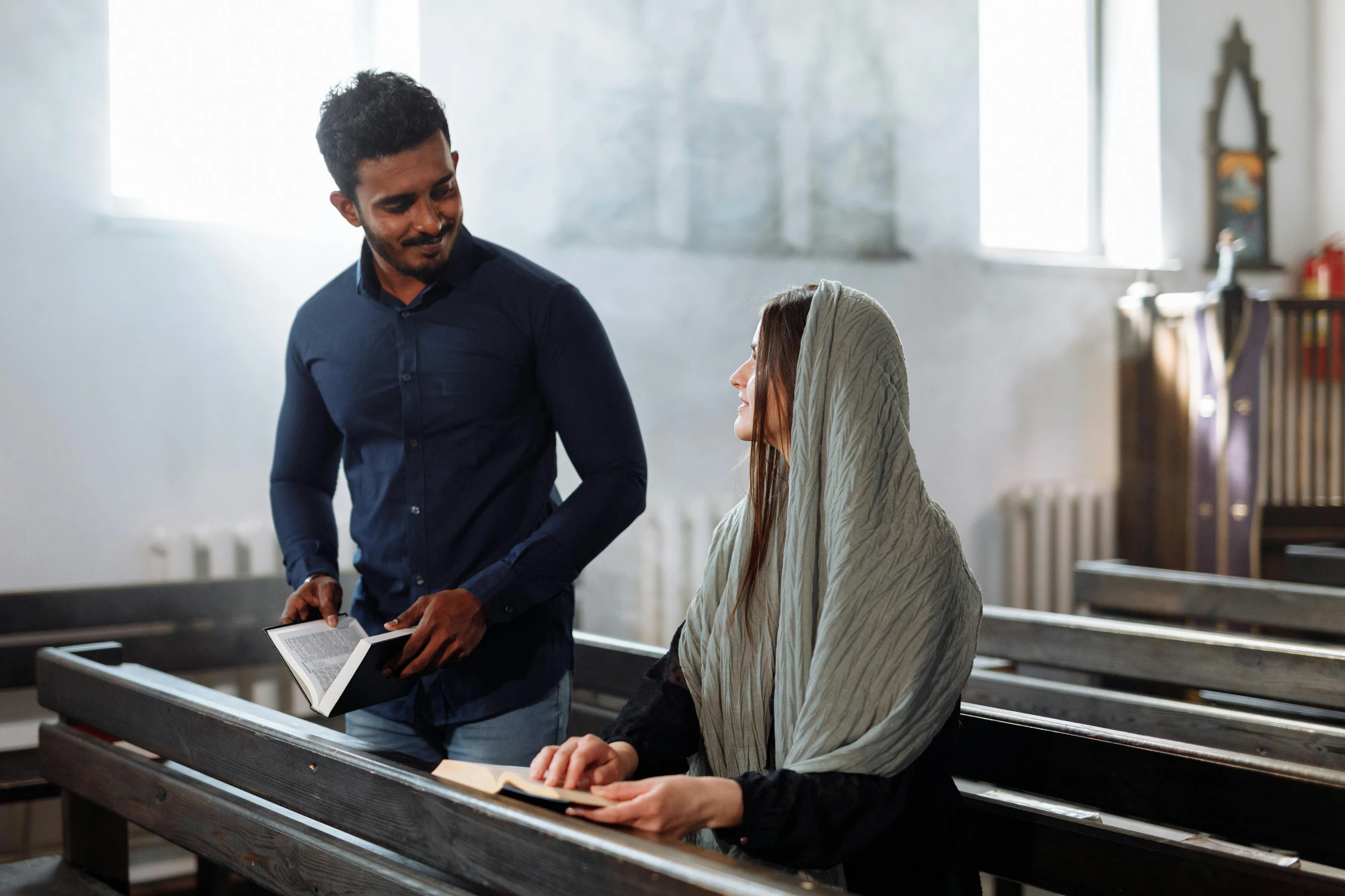 a priest and woman sitting down with an open bible