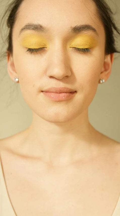 the face of a young woman with yellow eye makeup