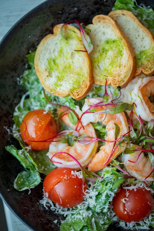 a pan with shrimp, bread and salad