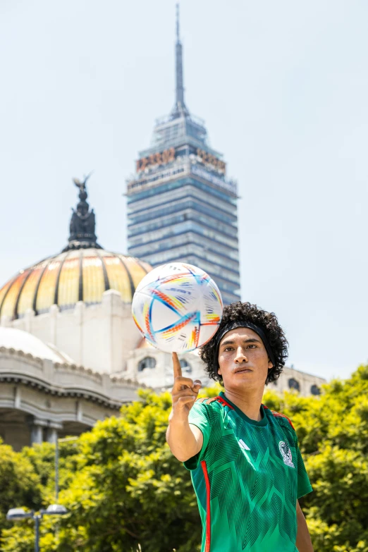 a man holding up a soccer ball in front of a building