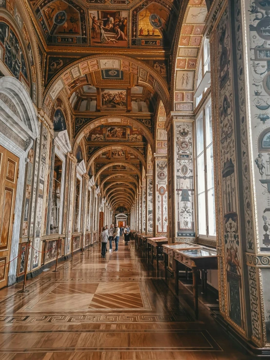 a hallway with an elaborate gold ceiling and wooden floors