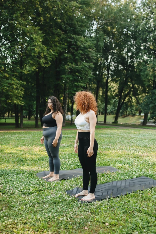 two women who are standing on some exercise mats in a park