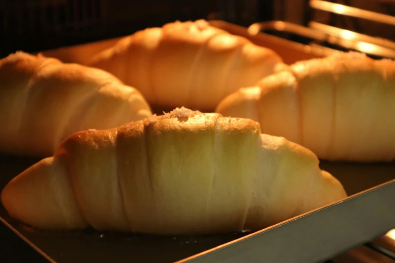 four large doughnuts are on a tray near a stove