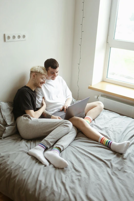 two young people sitting in bed with a laptop