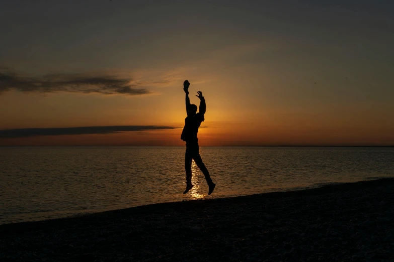 the person jumping in the air while standing at the beach