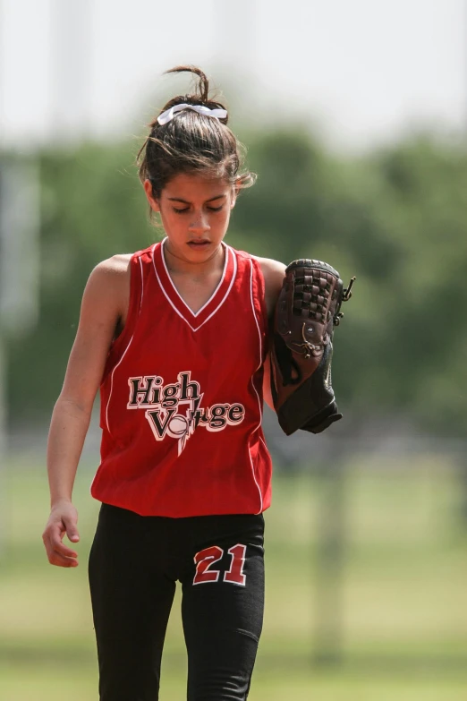 a girl in red jersey playing baseball with a catchers mitt