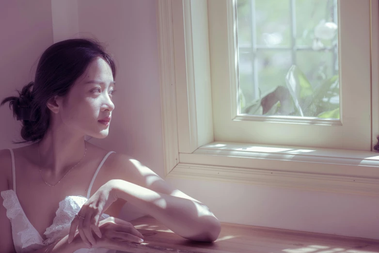 a woman looking out a window in a white shirt