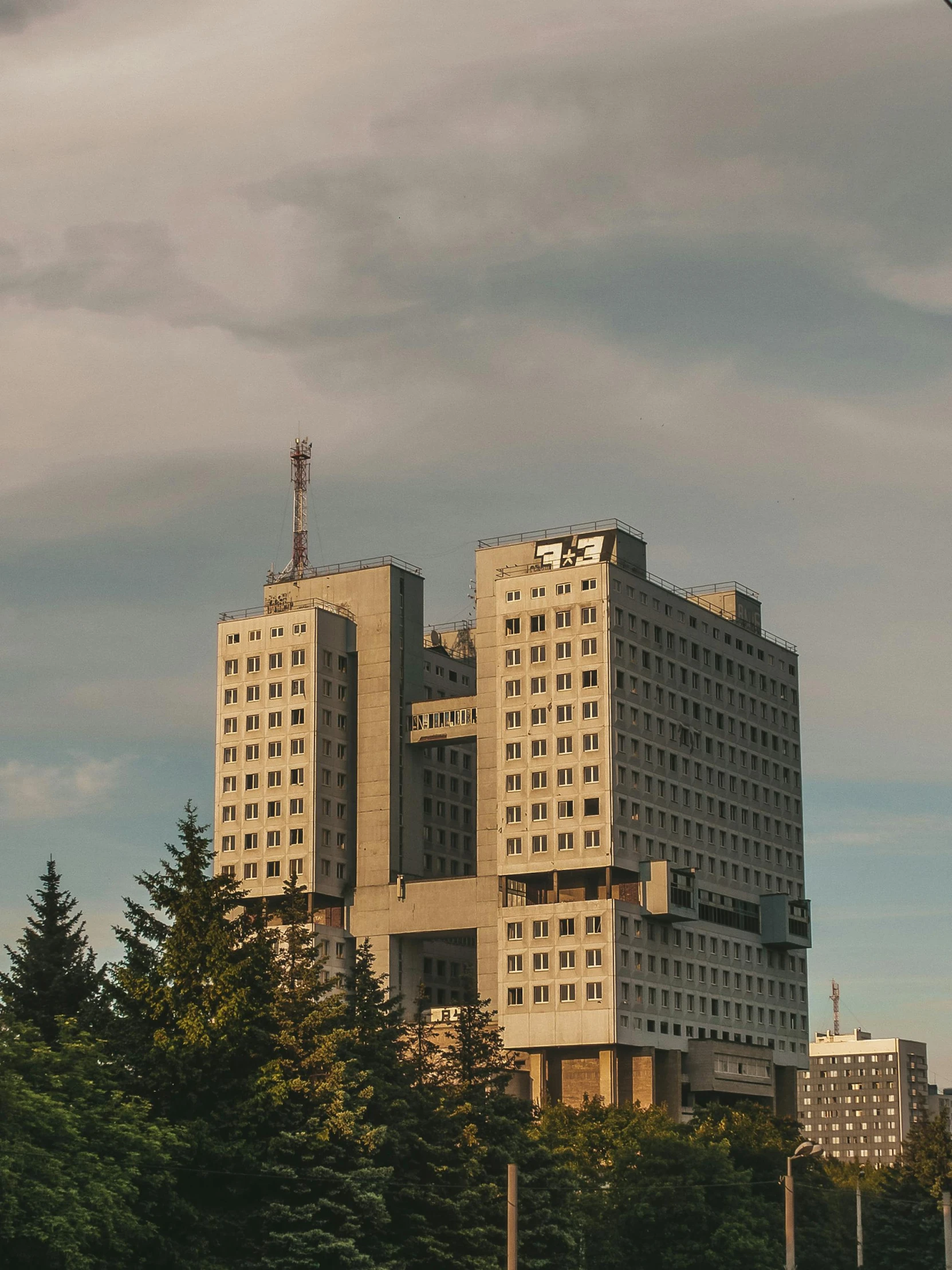 the white buildings with windows sit near a row of trees