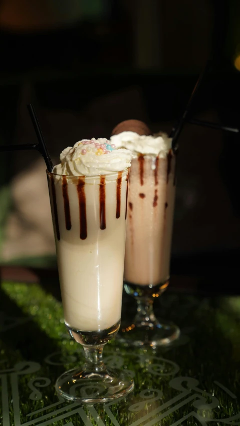 two beverages with some frosting on them are sitting next to each other