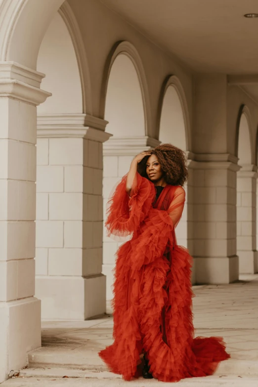 there is a woman wearing red that is standing under arches