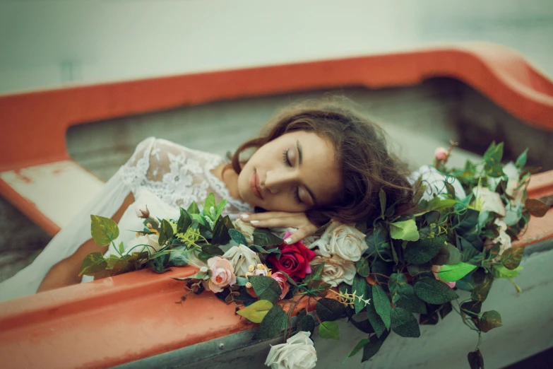 a woman wearing a dress and lying down in a boat