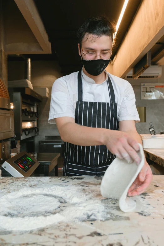 a man with a mask on puts dough into a bowl