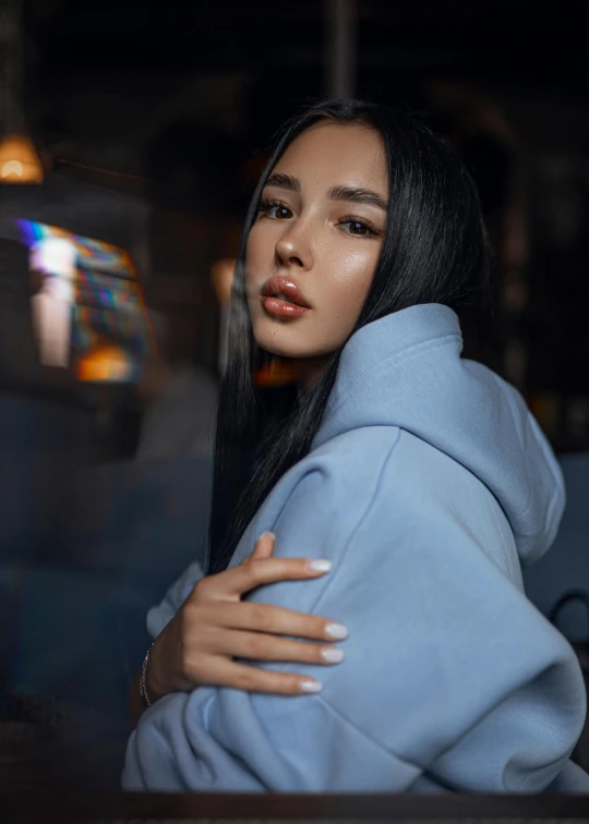 a woman sitting in a blue hoodie at a table