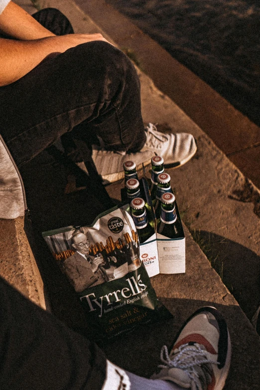 two people sitting on steps beside beer and magazines