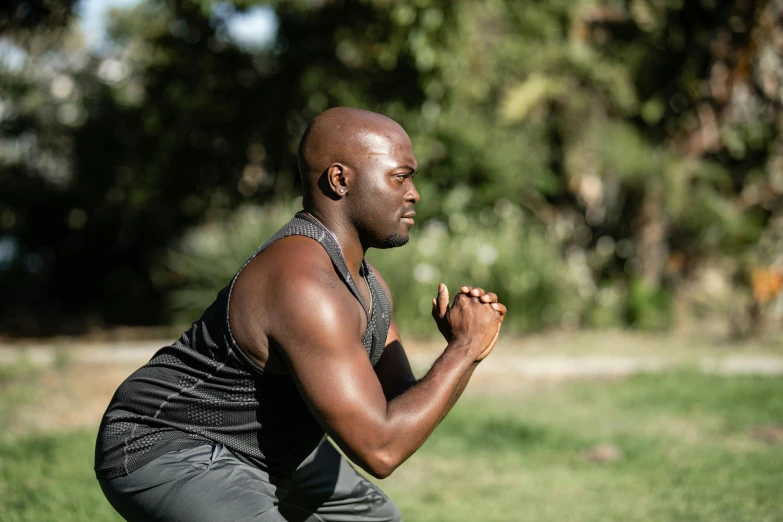 a man sitting down in a grassy area praying