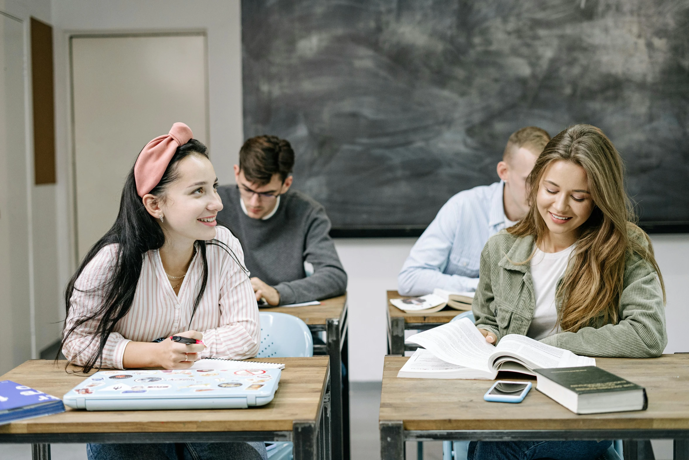 several young people seated at their desks while one reads