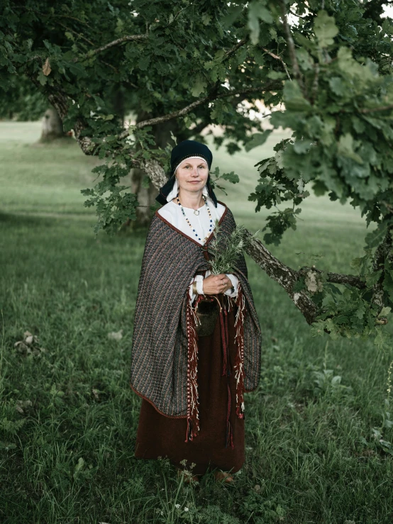 a woman in medieval clothing stands under trees