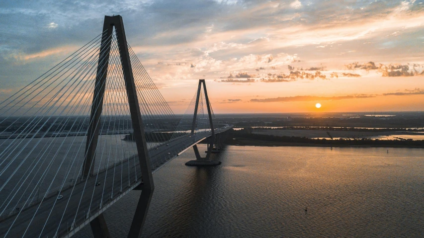 the sun setting behind an impressive suspension bridge