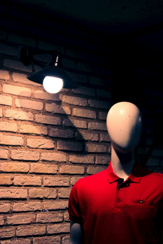 a mannequin in front of a brick wall with two lamps