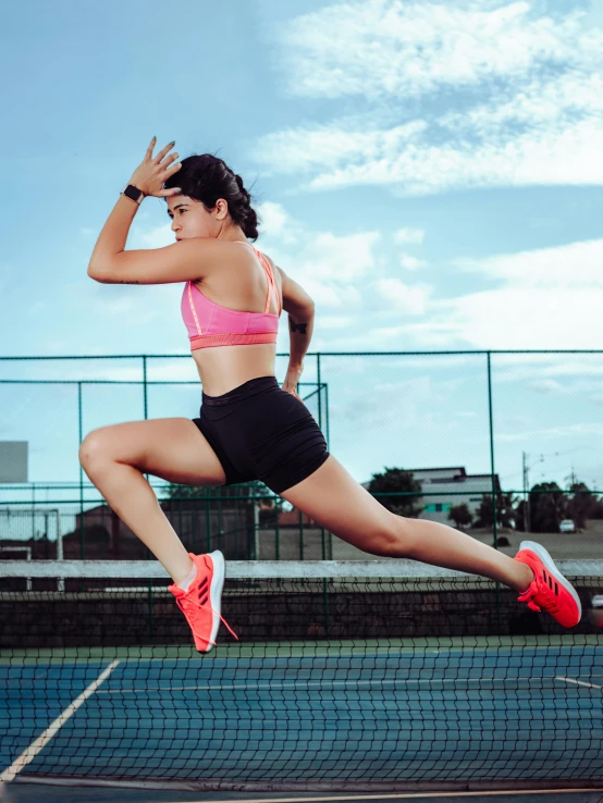 a woman is jumping in the air on a tennis court