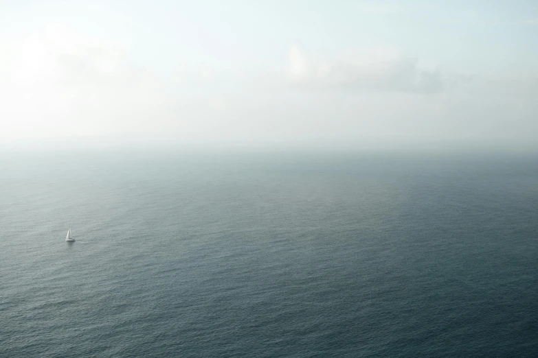 a lonely sail boat sailing through the ocean