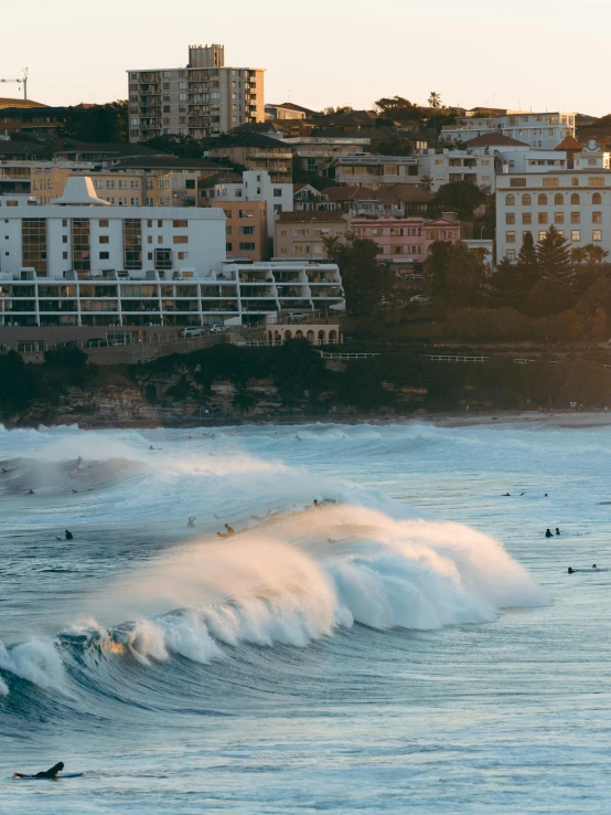 a large wave is riding in the ocean near houses