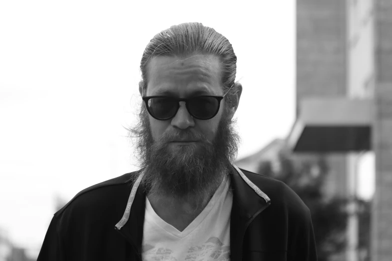a bearded man wearing shades and a sweater
