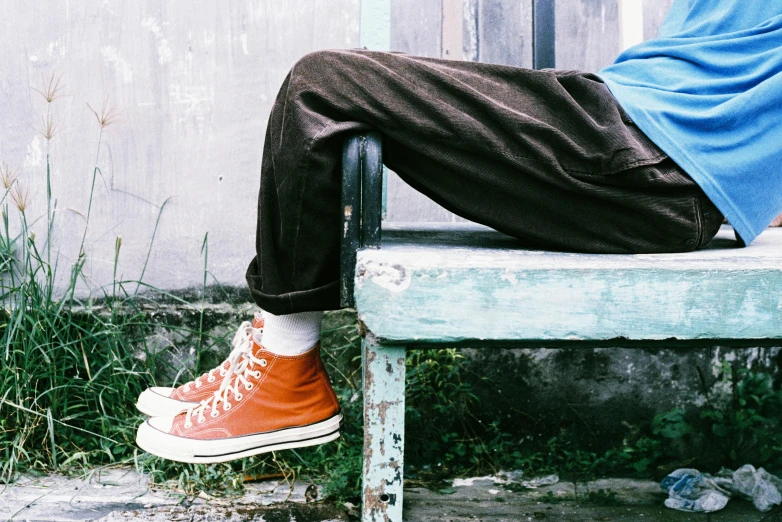 a person sits on a bench with their legs crossed