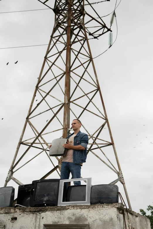 a man in a denim jacket is standing on top of a tower