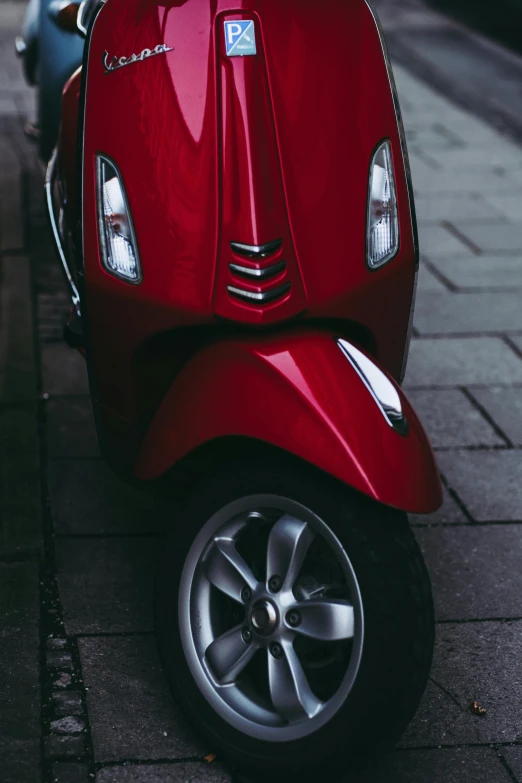 a red moped sitting on a road next to a sidewalk