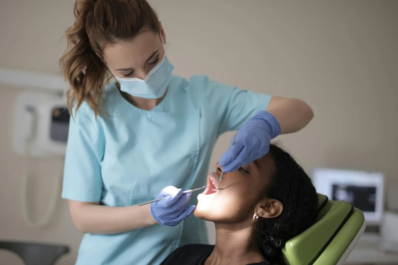 the woman is getting her teeth checked up by the dentist