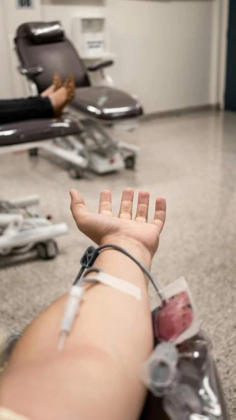 an arm wrapped in bandages sits in a room with a woman laying on the ground in the background