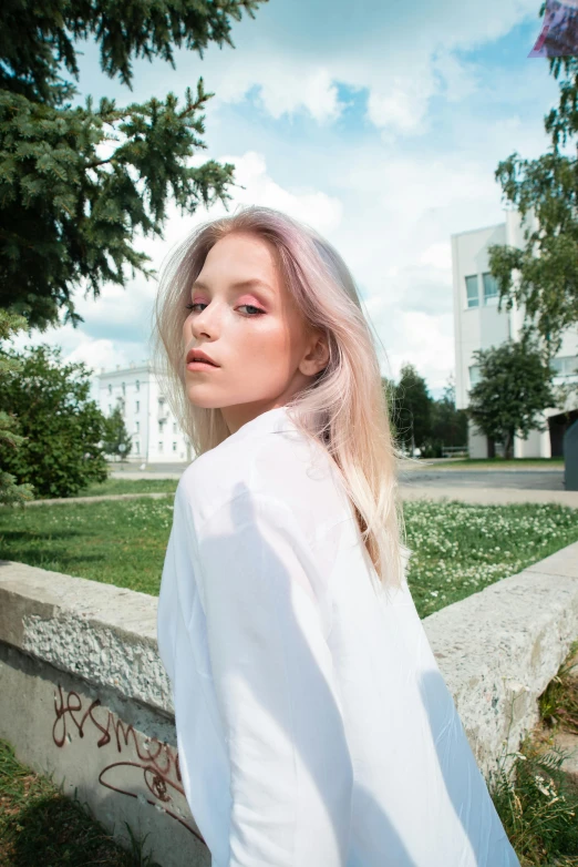 a woman with blonde hair is posing in a white top