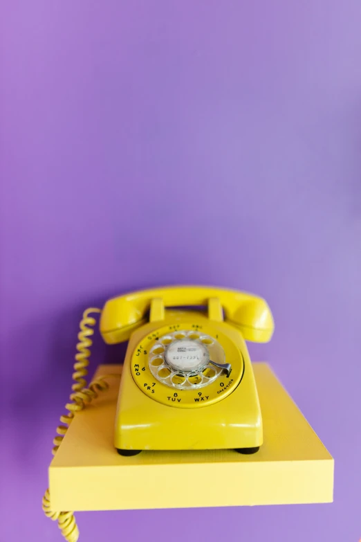 a yellow phone laying on top of a shelf