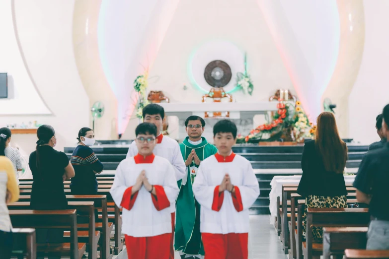 children in uniform stand at the front of a church pews