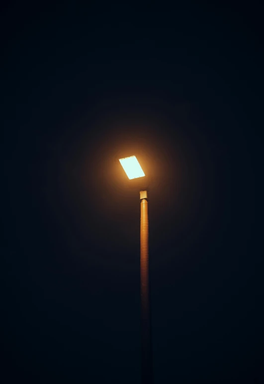 a lit up pole in the dark with a dark sky