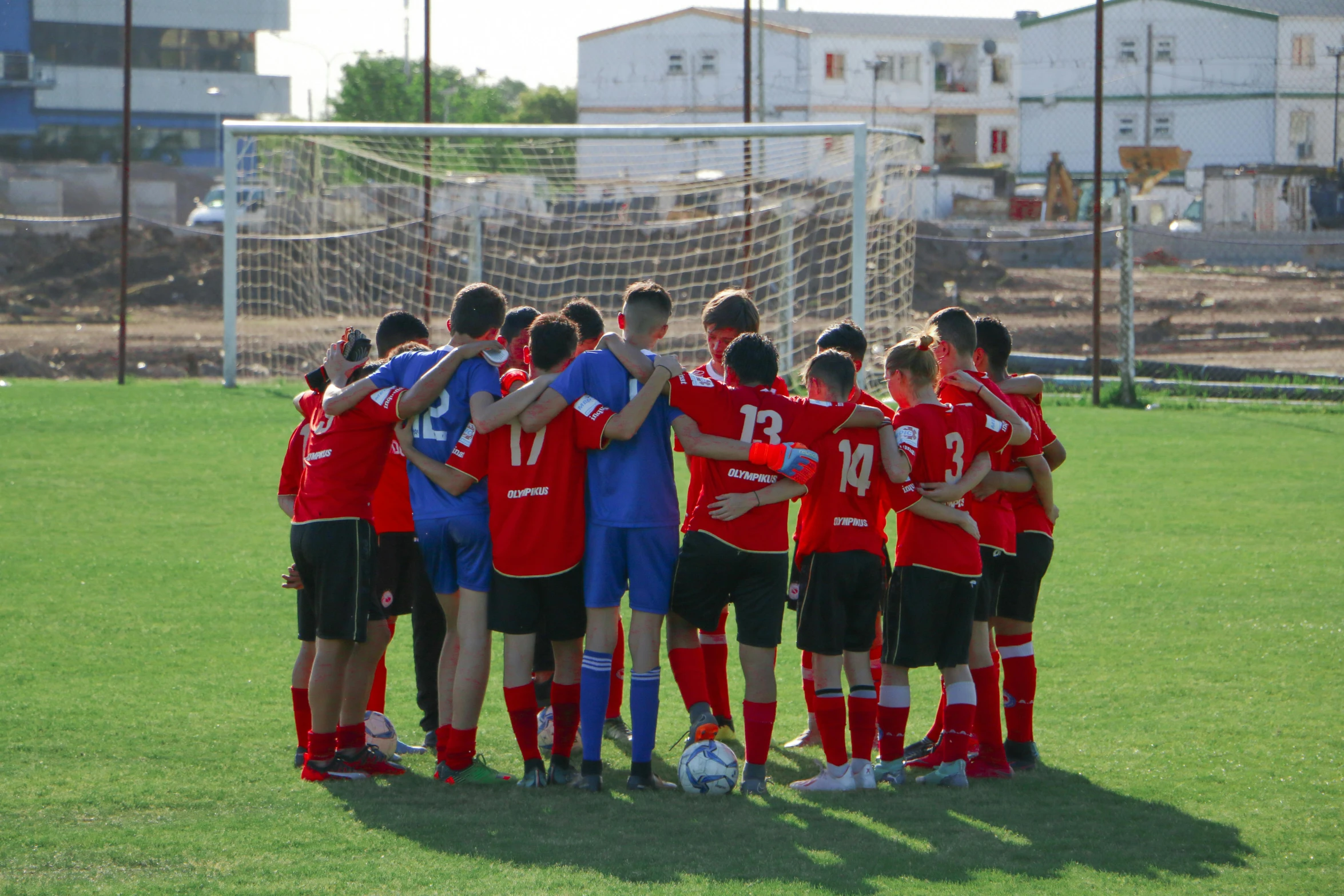 a group of young men in red soccer uniforms standing together on a soccer field