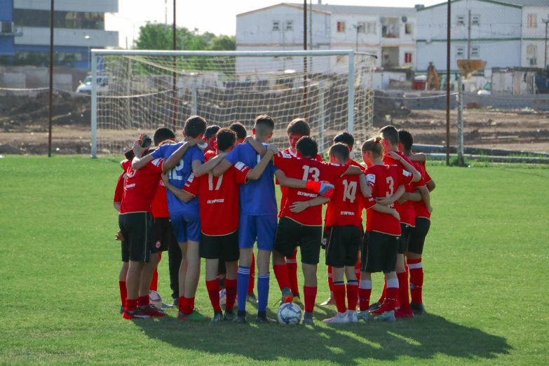 a group of young men in red soccer uniforms standing together on a soccer field