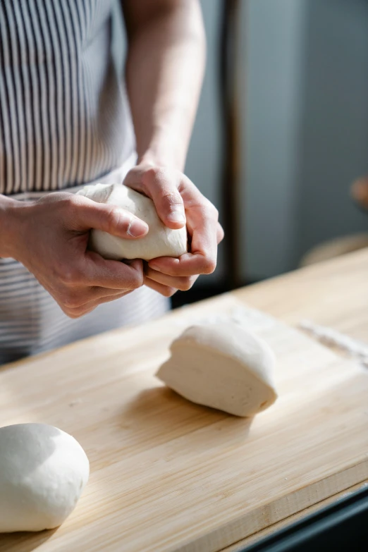 hands that are kneading dough onto a board