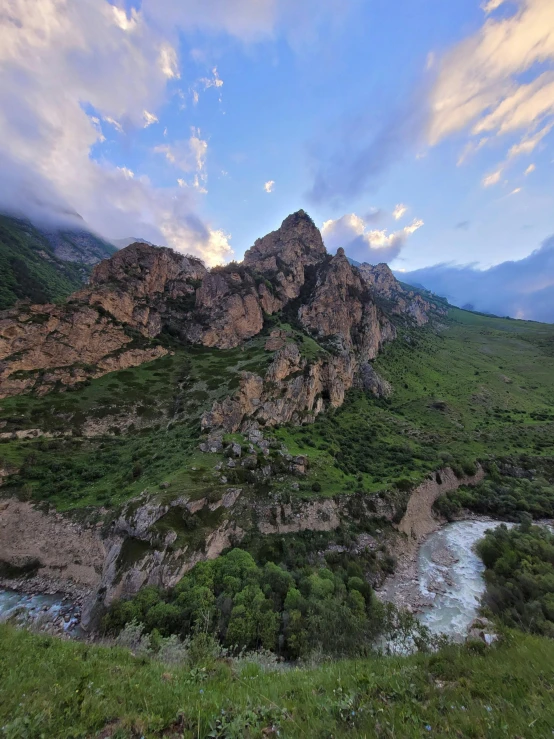 a river sitting between two large mountains next to some grass