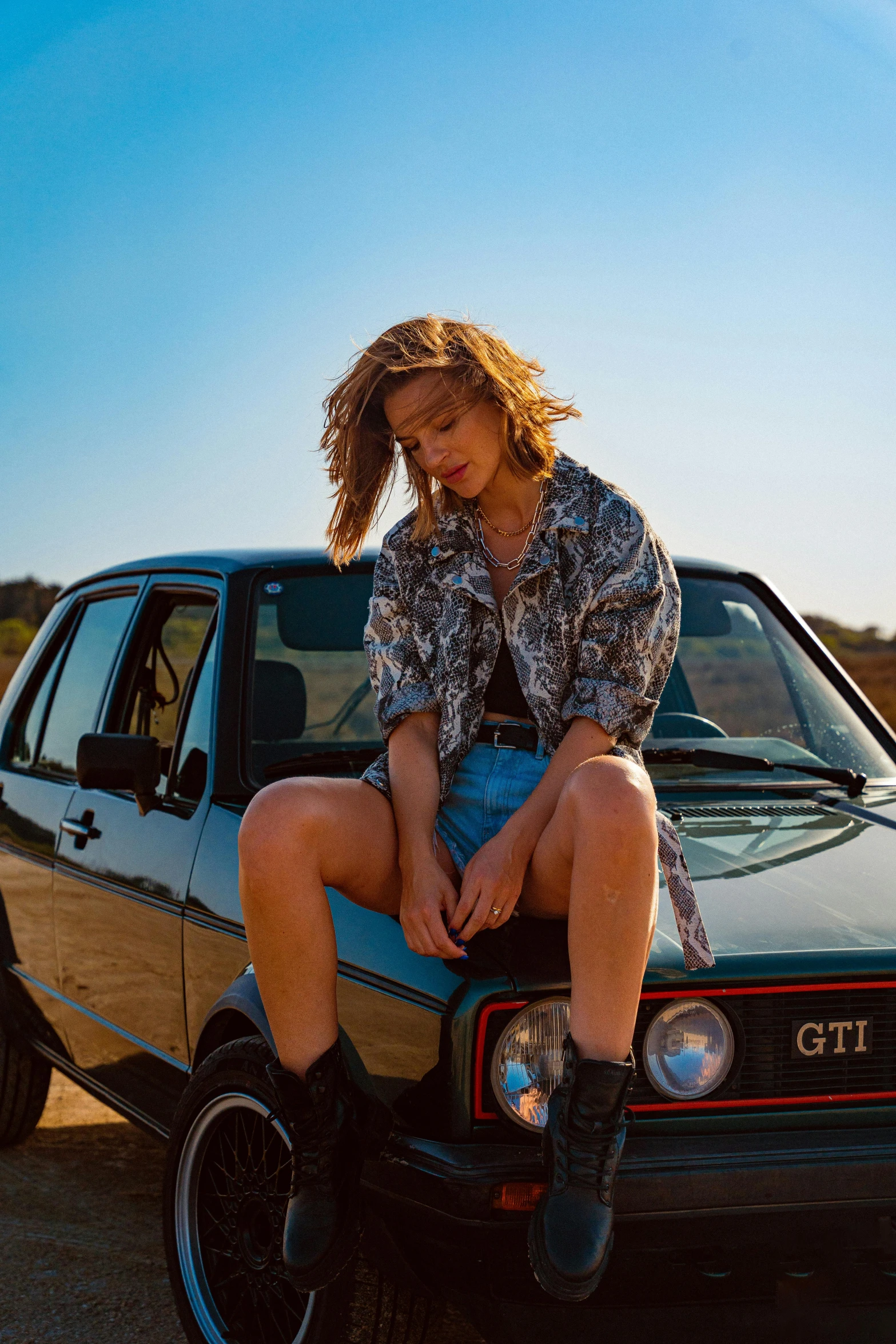  sitting on the hood of her small black car