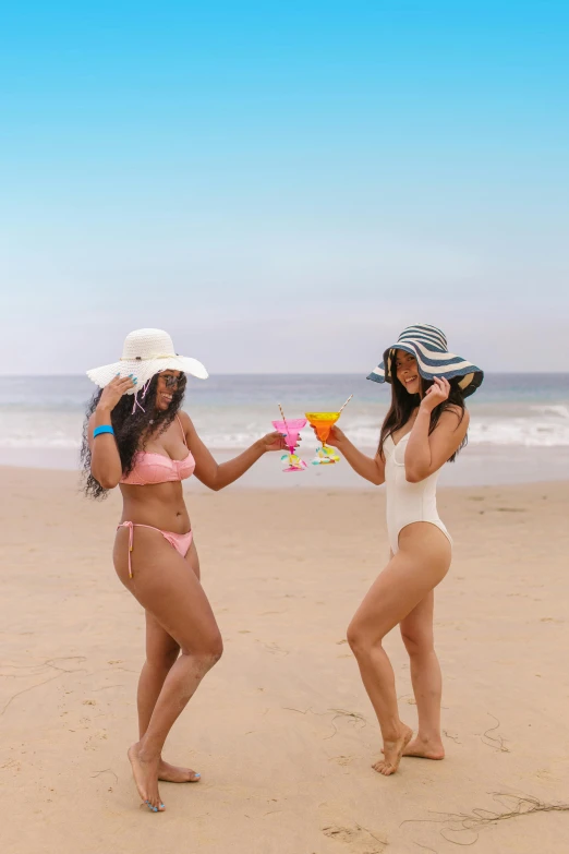 two women in bikinis toast with cocktail glasses