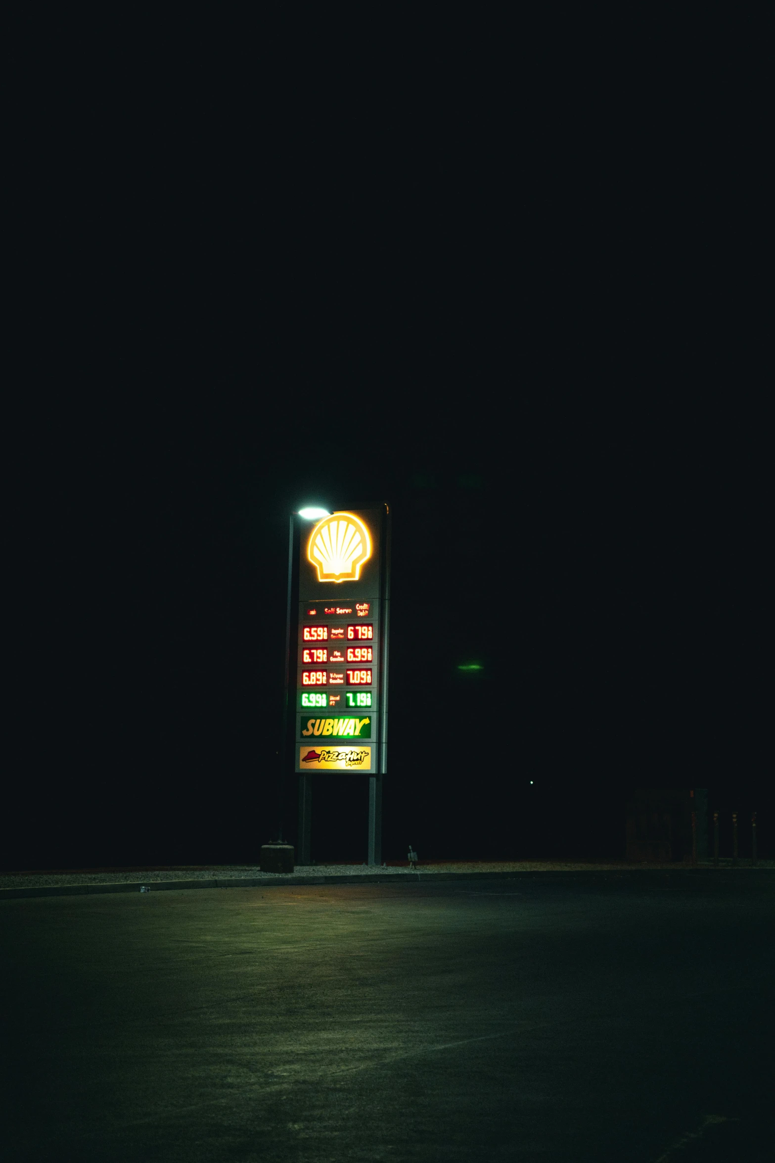 a lighted sign advertising an outdoor gas station