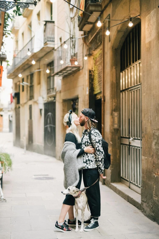 two people and their dog on the street kissing