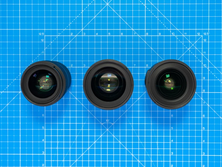 three lenses are shown sitting next to each other on top of a blue board