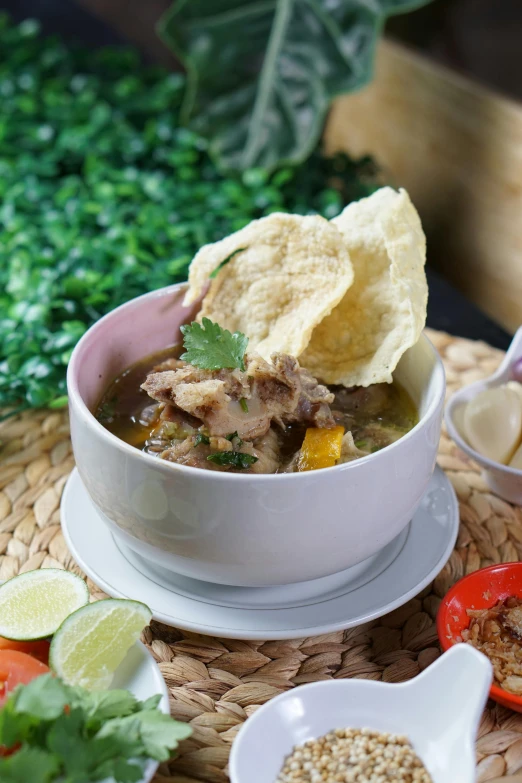 a bowl of chicken chili with tortilla chips and a cup of salsa