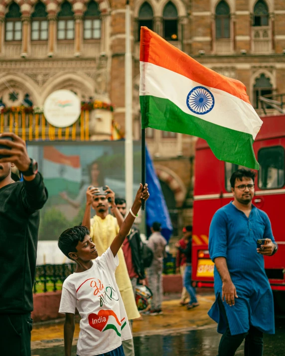 a little boy holding a flag while another boy is taking a picture