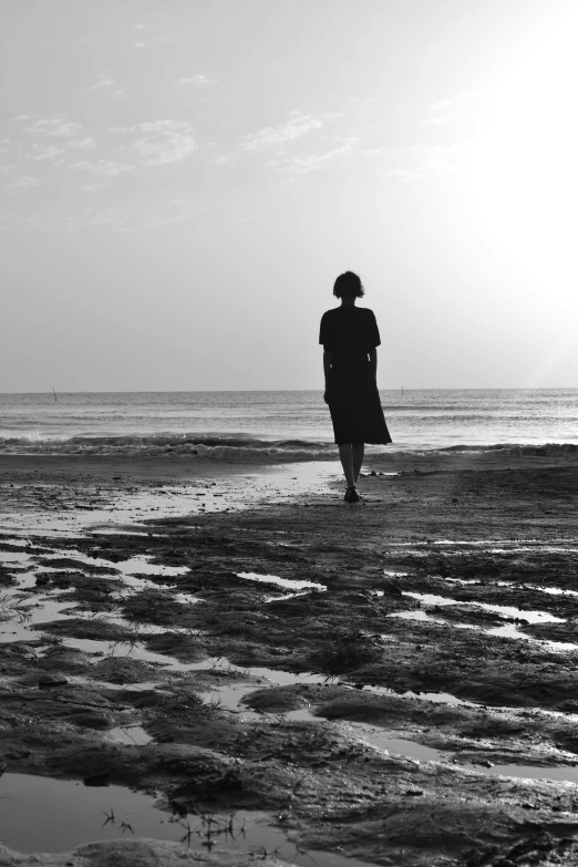 the back view of a woman walking along a beach